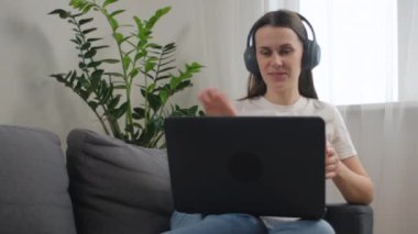 25 'li yaşlarda kulaklıklı mutlu bir kadın dizüstü bilgisayara bakıyor, video konferans konuşmalarıyla konuşan tatlı bir kız öğrenci, webcam ile öğretmenlik yapan bir bayan öğretmen, online eğitim. E-koçluk konsepti