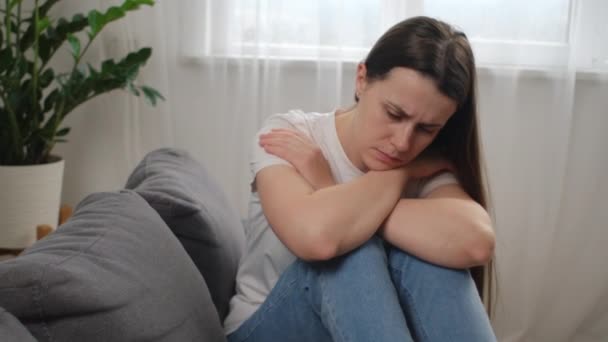 沮丧困惑的高加索女人感到不快乐 个人生活中的问题 与男朋友的争吵破裂和意外怀孕的观念 忧心忡忡的年轻女子坐在家里的沙发上 — 图库视频影像