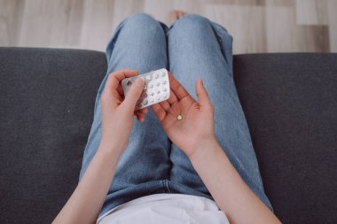 Genç bir kızın doğum kontrol haplarını açması, hormonal doğum kontrol hapları tutması, korunmak için ilaç alması, güvenli virüs seks hastalığı. Doğum kontrol ve hamilelik kavramı