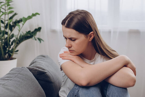 Разочарованная растерянная женщина чувствует себя несчастной, проблемы в личной жизни, ссора с парнем и неожиданная концепция беременности. Беспокоится, что молодая женщина сидит одна дома на диване