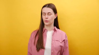 Yüzeysel jest yapan şanssız genç bir kadının portresi, pişmanlık ve keder hisseden, hata için kendini suçlayan, mağlubiyetten hayal kırıklığına uğrayan, stüdyodaki sarı arka plan duvarının arkasında izole edilmiş poz veren,