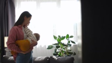Sevgi dolu bir annenin bebeğini emzirmesi, çocuk odasında pencerenin yanında durması, küçük oğluyla ilgilenmesi. Anne kollarında süt yiyen sessiz, aç bir bebek. Annelik, annelik.