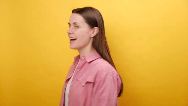 どうした 25歳の陽気な若い女性の肖像画は カメラを指し 魅力的な歯の笑顔で探し 指を示し 選択肢を作って 黄色のスタジオの背景の壁の上に隔離されています — ストック動画