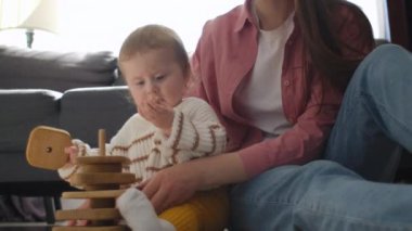 Sevgi dolu, genç bir anne, tahta küplerle küçük tatlı bir çocukla oynuyor. Mutlu, güzel bir dadı, modern, rahat bir evde güzel bir çocukla vakit geçiriyor. Çocuk gelişimi, eko oyuncağı, oyun zamanı konsepti