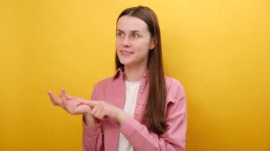 Oldukça olumlu 25 'li yaşlardaki genç bir kadının portresi parmaklarıyla rakamları gösteriyor, sayıyor ve gülümsüyor, stüdyodaki sade sarı arkaplan duvarında izole bir şekilde poz veriyor. Numara ve konsept hesapla