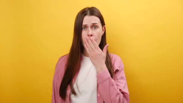 ショックを受けた顔をした悲しい若い白人女性の肖像画 ピンクのシャツを着て スタジオの平らな黄色の背景の壁の上に隔離された 表現の感情と感情のコンセプト — ストック動画