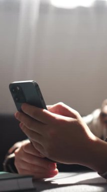 Kadın eli cep telefonunun dikey videosu. Meçhul genç kadın yeni taşınabilir e-randevu uygulamasından hoşlanıyor, mesaj konseptini paylaşıyor, sosyal medya ağlarından arkadaşlarıyla sohbet ediyor