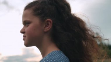 Yazın açık havada sevimli, mutlu küçük bir kızın portresi. Tatlı, rüya gibi, güneşli, güzel bir günün tadını çıkaran, çayırda duran ve gülen bir çocuk. Halk özgürlüğü ve çocukluk kavramı