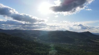 Karpatlar 'daki kayan tepelerin gökyüzü manzarası. Evleri, tarlaları ve güneşli dağları ılık yaz günlerinde.