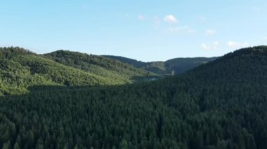 Gün batımında mavi gökyüzüne bakan güzel yeşil dağların insansız hava aracı görüntüleri. Arka planda sıradağlar var. Temiz ve huzurlu bir manzara. Keşif ve seyahat hedefi