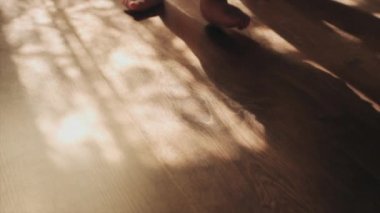 Meçhul bir anne ve küçük bir çocuk. Çocukluk konsepti. Zeminde yürüyen küçük ayakların seçici odağı. Bebeğin evde yürümeyi öğrenmesine yakın çekim. Bebek ilk adımları