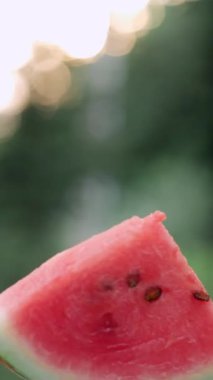 Taze dilimlenmiş karpuzun dikey görüntüleri. Yaz günbatımında arka plandaki tabakta sulu karpuz dilimler. Seçici odak