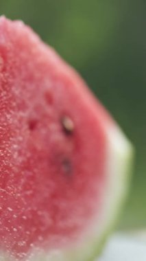 Sıcak yaz zamanında doğanın arka planında dönen sulu karpuzun dikey videosu. Ferahlatıcı ve lezzetli meyveler. Meyve konsepti. Seçici odak