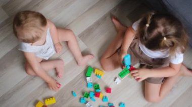 Evde renkli küp oyuncaklarla oynayan meraklı çocukların en iyi manzarası. Güzel küçük kız ve erkek bebek anaokulunda inşaatçı küpleriyle oynuyorlar. Mutlu aile okul öncesi eğitim konsepti