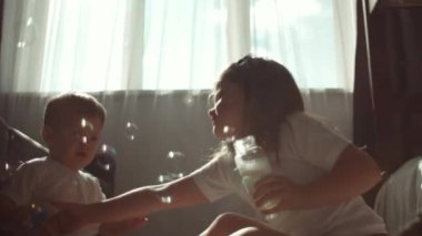 Evdeki sıcak salonda oturan sevimli komik çocuklar baloncukları üflüyorlar. Erkek ve kız kardeşler sabun köpüğü patlatıyorlar. Mutlu çocuklar sabun köpüğüyle oynuyorlar. Çocukların kapalı mekan oyun konsepti