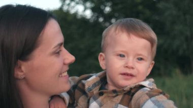 Dağın arka planında yeşil ormanlara karşı sevgi dolu, çocukların ruhsal sağlığına özen gösteren, özenli ve nazik şefkat kavramına dikkat eden mutlu bir anne ve güzel bir oğlan çocuğunun portresi.