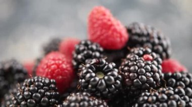 Arka plandaki taze böğürtlen ve ahududu dönüşlerini kapatın. Kırmızı ve siyah dutlar. Doğadan gelen vitaminler. Yaz yemekleri konsepti. Seçici odak