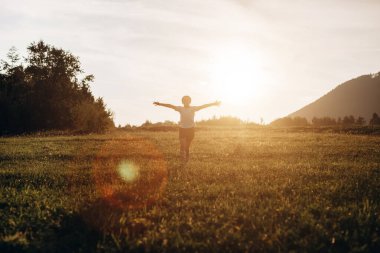 Arka plandaki dağlarda koşan ve güzel günbatımında gökyüzünde koşan çocukluk çağındaki oyuncu kız. Çocuk kollarını bir uçağın kanatları gibi kaldırarak koşuyor, çocukluk hayali tatili. Çocuk rüyası, uçak pilotu