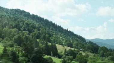 Sıcak, güneşli bir günde araba penceresinden, bulutlu gökyüzünden ve güzel yaz dağlarından manzara. Doğada arabayla seyahat etme kavramı. Yavaş çekim