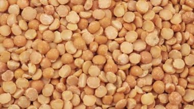 Kurumuş bezelyelerin üst görüntüsü. Yulaf lapası pişirmek için yuvarlak sarı bezelyeler, pişirmeden önce etrafa saçılmış çiğ bezelyeler. Sağlıklı gıda konsepti. Yavaş çekim