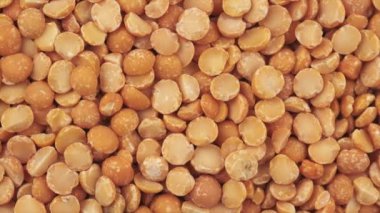 Dönüşün en üst görüntüsü birçok kurutulmuş bezelye. Yulaf lapası pişirmek için yuvarlak sarı bezelyeler, pişirmeden önce saçılmış çiğ bezelyeler. Sağlıklı gıda konsepti. Yavaş çekim