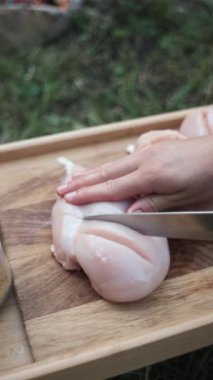 Kadın ellerinin yemek yaparken çekilmiş dikey görüntüleri akşam ateşinin yanında ahşap tahtada tavuk kesiyor. Sağlıklı yaz yemekleri. Kamp yapan ve dışarıda parti veren insanlar.