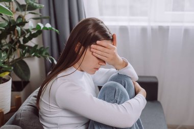 Depresyondaki genç esmer kadın ifadesi, sorun hakkında düşünmeyi, koltukta oturmayı, zorluğu, başarısızlığı ve bitkinliği, yalnızlığı, kederi ve kötü ilişkiyi düşünmeyi ifade eder.