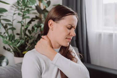 Yorgun, genç bir kadın. Boyun ağrısı, işten dolayı vücut ağrısı, masaj, omuz ağrısı, evdeki kanepede otururken ağrısı. Ağrı, kas sertleşmesi sorunu. Sağlık ve Tıp Konsepti