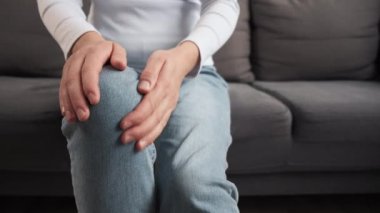Vücut eklem iltihabı kasları sorunlu kavram. Bacak ağrısı çeken genç bir kadın, kronik hastalıktan dolayı diz ağrısı, el masajı eklem yaralanması, kadın yaralanması ya da evdeki kanepede otururken ağrısı.
