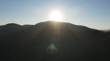 Muhteşem sıcak günbatımında, güzel sonbahar dağlarının, tepe noktasının ve renkli ormanın insansız hava aracı görüntüsü. Gün batımları ufukta alacakaranlık ya da şafak saatlerinde. Huzurlu bir akşam doğa ve kamp havası.