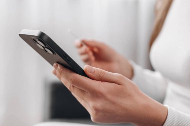 Kadınların elinde kredi kartı ve akıllı telefon, internette ödeme yapan genç bir kadın, bankacılık hizmetini kullanarak, bilgi girerek, alışveriş yaparak, internet mağazasından sipariş vererek, güvenli ödeme yaparak,