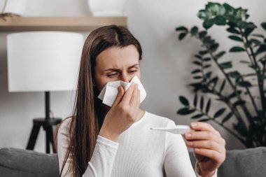 Hastalıklı sağlık hizmetleri, salgın virüsler. Hasta gripli genç bir kadın yorgun ve ateşi var. Öksürük kontrol için termometreyi tutuyor. Vücut ısısını ölçmek için.