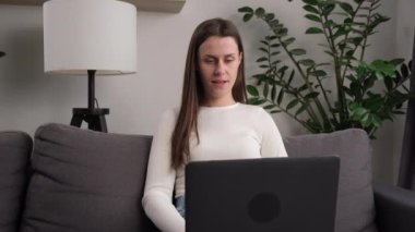 Piyango galibiyetini ya da başarısını kutlayan neşeli, genç bir kadın, dizüstü bilgisayar ekranına bakıyor, iyi haberler alıyor, online alışveriş için indirim yapıyor, sürpriz jestler yapıyor.