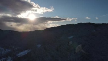 Soğuk akşam manzarasında, kar ve karlı ağaçlarla dolu kış dağlarında güzel günbatımının hava aracı görüntüsü. Açık hava yaşam tarzı sağlıklı ve temiz hava için.