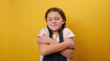 Sarılmak için ellerini uzatan, bedava kucaklaşan ve karşılayan, stüdyodaki sarı arka plan duvarında izole edilmiş mutlu genç kız portresi. Çocukluk yaşam tarzı konsepti