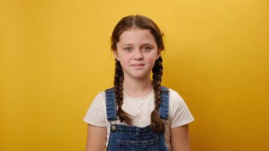 Heyecanlı genç kız çocuk portresi kazanan hareketli yumruk hareketi yapar. Stüdyodaki sarı arka plan duvarında izole bir şekilde poz verir. Çocukluk yaşam tarzı konsepti
