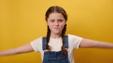 Güçlü spor fitness prematüre kız çocuğunun portresi elinde pazı kaslarını gösteriyor, stüdyodaki sade sarı arka plan duvarının üzerinde izole bir poz veriyor. Çocukluk yaşam tarzı konsepti