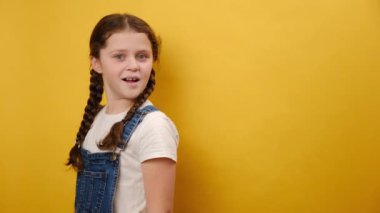 Küçük, şirin bir kızın portresi fotokopi çekilirken başparmağını bir kenara koyup stüdyodaki sade sarı arka plan duvarının üzerinde izole bir poz veriyor. Çocukluk yaşam tarzı konsepti