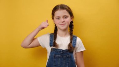 Küçük yaşta gülümseyen güzel bir kızın portresi beni ara diyor. Stüdyonun sarı arka plan duvarında izole bir şekilde poz veriyor. Çocukluk yaşam tarzı konsepti