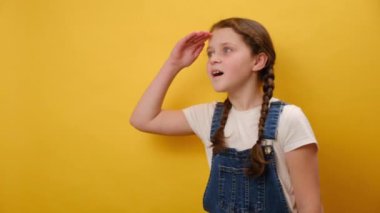 Çok tatlı bir çocuk portresi. Alnından el ele tutuşup uzaktaki bir yere bakıyor. Stüdyodaki sarı arka plan duvarında izole bir şekilde poz veriyor. Çocukluk yaşam tarzı konsepti