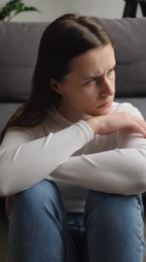 Mutsuz, kaygılı, diziyle yüzünü kapatan genç bir kadının depresyondaki kalbi kırık bir kadının psikolojik sorunları olduğunu gösteren dikey bir video.