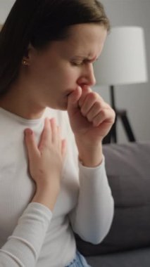 Kafkasyalı bir kadının kanepede oturduğu, soğuk algınlığı, öksürük, hapşırma, hasta bir kadının evde öksürme, grip konsepti gibi hastalıklı belirtilerin olduğu dikey videolar.