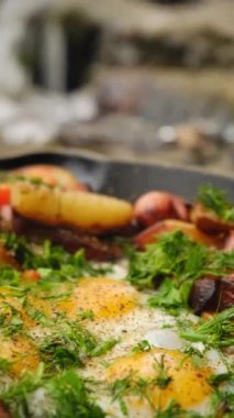 Tavanın dikey görüntüleri, iştah açıcı patates yumurtaları, yeşil maydanoz ve sebzeler sakin kış gününde dağların yanında kızartılmış. Yemek pişirme konsepti