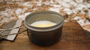 Bilinmeyen genç adam kış ormanında kremalı peynir sosu yapıyor. Yemek pişirme konsepti