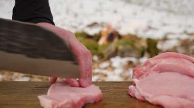 Bilinmeyen genç adama yakın çekim yapmak için kamp yaparken ya da kış zamanı yürüyüş yaparken şenlik ateşinin yanında taze et hazırlıyor. Açık hava pişirme konsepti
