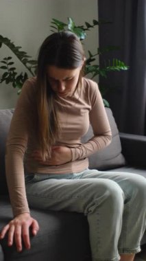 Karın ağrısı çeken hasta bir kadının dikey görüntüsü karın ağrısı, mide iltihabı, pankreas semptomları. Kadın koltukta oturup hazımsızlık çeken mide gazından muzdarip.