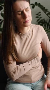 Sağlıksız beyaz bir kadının göğüslerine dokunup evde tek başına oturduğu dikey görüntüler. Göğüs kanseri kontrolü. Sağlık ve Tıp Konsepti