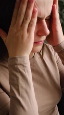 Kafasına dokunan ve baş dönmesi, baş ağrısı ve migren ağrısı çeken yorgun ve bitkin bir kadının olduğu dikey bir video. Kriz kavramı