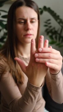 Bilek ağrısı ve romatizma iltihabı olan üzgün kadın masaj elinin dikey görüntüleri. Genç kadın elindeki uyuşukluk, uyuşukluk parmak ucu, eklem iltihabı, çevresel nöropati.