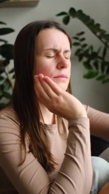 Yanağa dokunan bir kadının dikey görüntüsü, dişleri ağrıyan bir kadın. Mutsuz olmak kötü hissettiriyor. Ağızda hastalık, sinir ağrısı ve azı dişi. Diş ağrısı ve diş sağlığı, çene ağrısı, sağlık konsepti